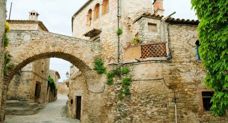 Ruelle pavée bordée de maisons en pierre dans un village médiéval catalan