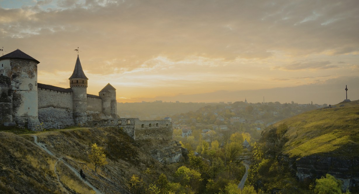 Château médiéval aux tours imposantes au coucher de soleil avec ville historique en contrebas