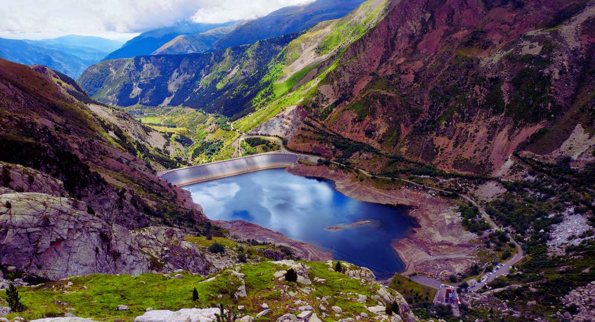 Vue panoramique sur un lac d'altitude dans les Pyrénées depuis un col de montagne avec vallée verdoyante