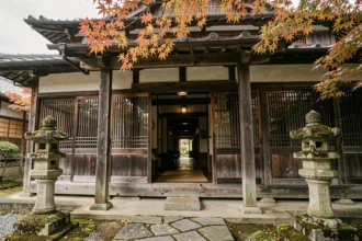 Façade en bois ancien d'une auberge traditionnelle japonaise, la plus vieille du monde, avec lanternes en pierre et chemin de pierres irrégulières
