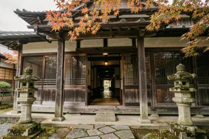 Façade en bois ancien d'une auberge traditionnelle japonaise, la plus vieille du monde, avec lanternes en pierre et chemin de pierres irrégulières